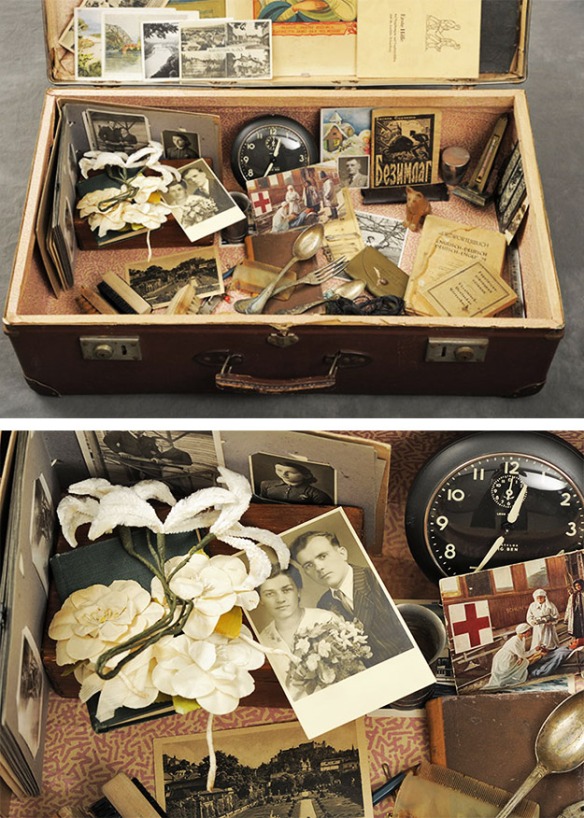 Open suitcase with vintage family photos, clock and fork and knife.