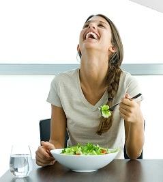 Advertisement with woman laughing alone with salad.