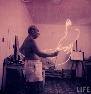 Pablo Picasso shirtless, painting with light.