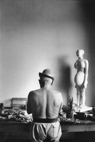Pablo Picasso shirtless with bowler hat and drawing model.
