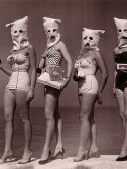Contestants pose on beach with creepy bags placed over their heads.