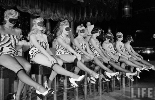 Contestants of beautiful legs contest wear masks and striped bathing suits, 1949.