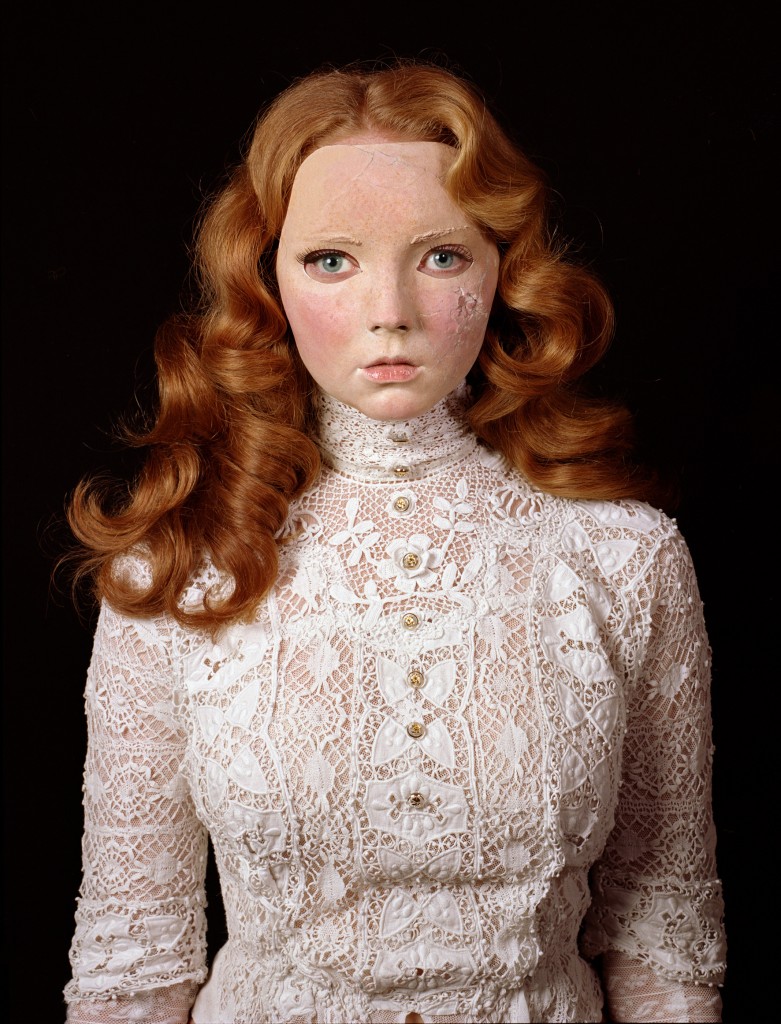 Photograph of model Lily Cole wearing a Victorian lace blouse and a damaged mask of her own face